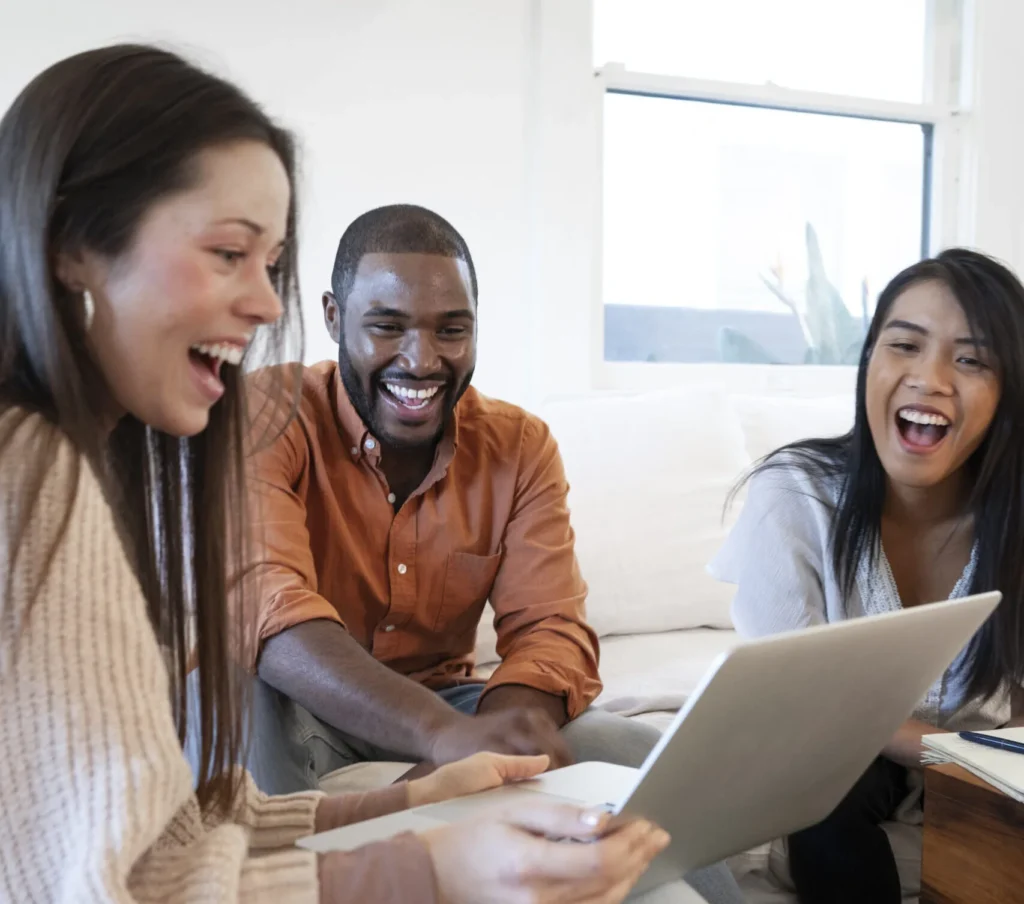 3 young people sitting around laptop at work, laughing and excited over their new website created by Matt Chase Designs